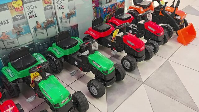 Plastic toy tractors displayed on a store floor. Tbilisi, Georgia - May 3, 2025.