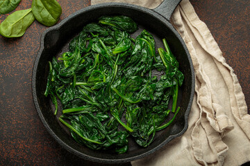 Freshly steamed spinach leaves are served in a cast iron pan, a nutritious and flavorful side dish or ingredient for healthy meals
