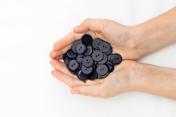 Numerous black buttons in the hands of a woman