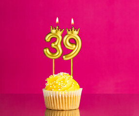 Yellow birthday cupcake with a number 39 candle - Birthday card on a pink background