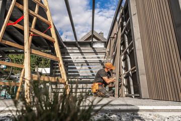 Craftsman Installs Wooden Panels in Contemporary Architectural Space During Bright Daylight Hours