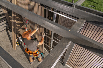 Construction Worker Climbs Ladder to Install Framework at a Residential Site During Sunny Day