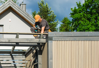 Construction Worker Completing Roof Work on a Residential Building in Sunny Weather