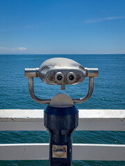 Coin operated telescope at Malibu Pier, California, USA against sea and blue sky