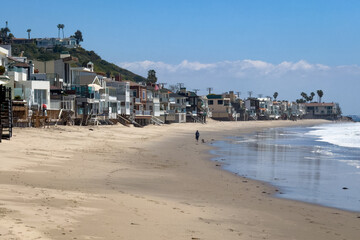 Beach house on stilts near water edge at Carbon-La Costa Beach in Malibu, California, USA against blue sky