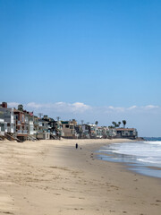 Beach house on stilts near water edge at Carbon-La Costa Beach in Malibu, California, USA against blue sky