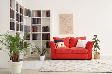 Red sofa and bookshelves in light living room © Pixel-Shot