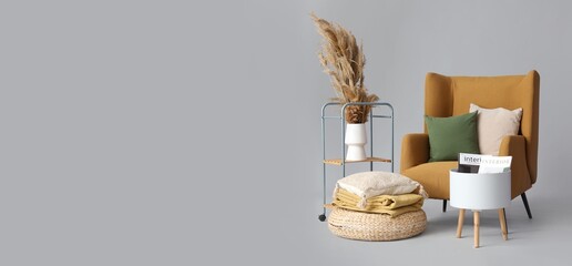 Armchair, vase, pouf and table on grey background with space for text