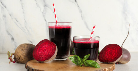 Glasses of fresh beet juice with basil and vegetables on white background
