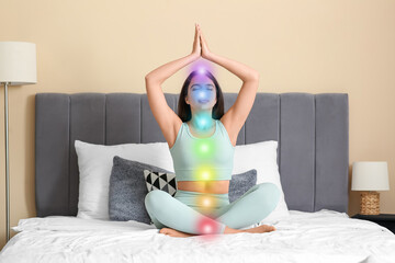 Beautiful young woman doing breath practice and meditating on bed at home