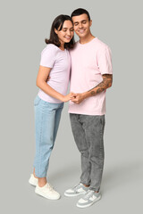 Happy young couple hugging on grey background