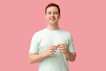 Handsome young man with lip balm on pink background
