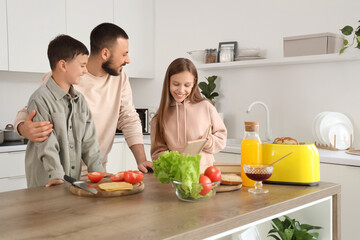 Cute little children with their father preparing sandwiches at home