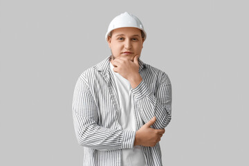 Young male engineer on grey background