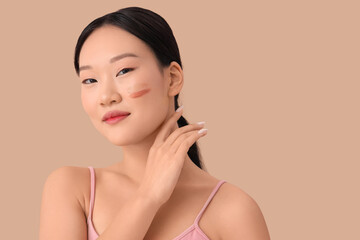 Beautiful Asian woman with samples of tonal foundations on beige background