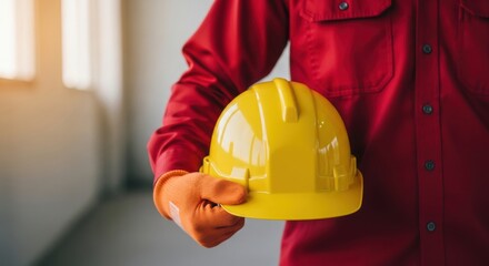 Worker holding yellow hard hat symbolizing safety and construction