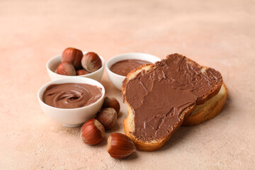 Bread slices with sweet chocolate spread and hazelnuts on beige background