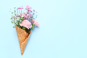 Ice cream cone with beautiful flowers on blue background