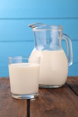 Fresh milk on wooden table against light blue background, closeup