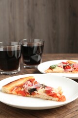 Slices of tasty pizza with thin smoked sausages served on wooden table, closeup