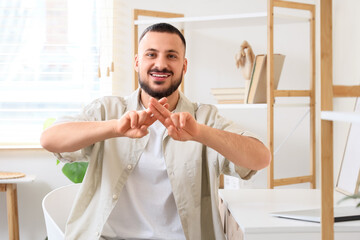 Young mute man using sign language at home