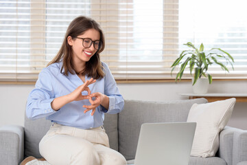 Young mute woman using sign language during video call at home