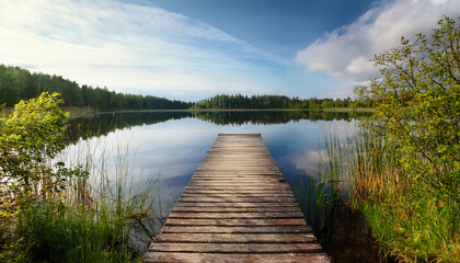 Obraz premium an old wooden dock above a small calm lake