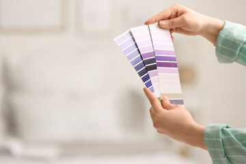 Female hands with violet paint palette swatches at home, closeup