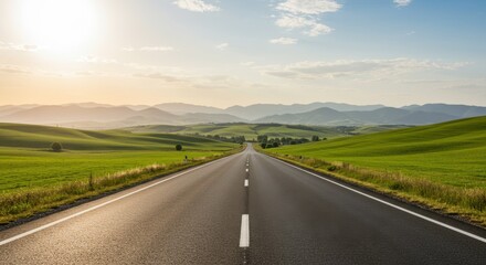 Fototapeta premium Scenic road stretching through rolling green hills under a bright sky at sunset