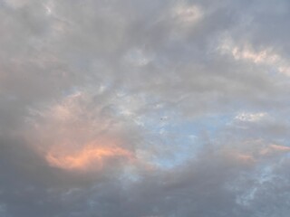 The expansive sky is dominated by soft, layered cloud formations, featuring varying shades of gray, white, and a touch of orange, perfect as a calming backdrop, for projects that require natural