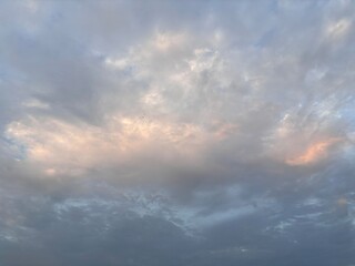 The expansive sky is dominated by soft, layered cloud formations, featuring varying shades of gray, white, and a touch of orange, perfect as a calming backdrop, for projects that require natural