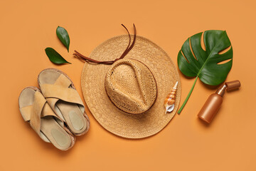 Summer composition with beach accessories, bottle of sunscreen cream and tropical leaves on orange...