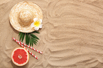 Fototapeta premium Summer composition with tropical leaf, grapefruit and wicker hat on sand as background