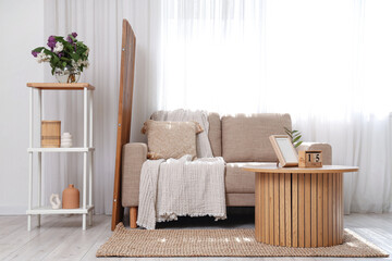 Wooden coffee table, shelving unit and sofa in interior of living room