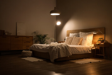Interior of dark bedroom with tables and glowing lamps