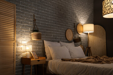 Interior of dark bedroom with table, plants and glowing lamps