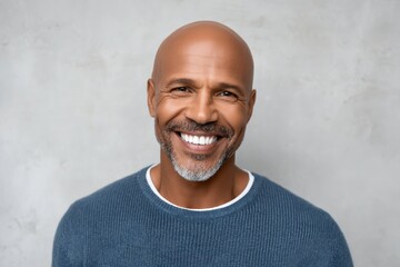 Smiling bald african adult male in blue sweater against neutral background