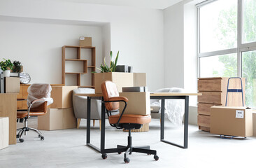 Packed boxes with belongings and furniture in new office on moving day