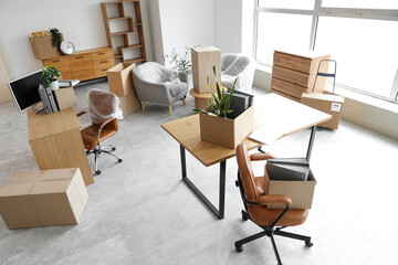 Packed boxes with belongings and furniture in new office on moving day