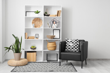 Interior of light room with bookshelf, plants and armchair
