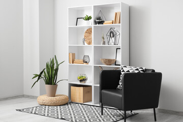 Interior of light room with bookshelf, plants and armchair
