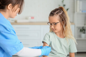 Little girl with doctor applying patch after vaccination in clinic