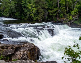 Fototapeta premium Cascading Waterfall with Lush Greenery and Rocky Riverbank