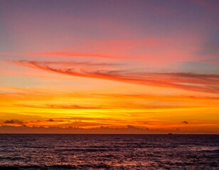 Fototapeta premium Vibrant Sunset Over Calm Ocean with Cloudy Sky and Gentle Waves
