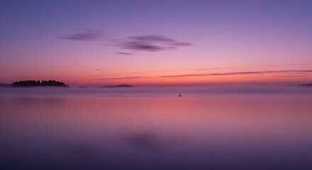 Naklejka premium Serene Foggy Sunrise over Calm Lake with Island Silhouette