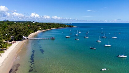 Obraz premium Serene Beach with Calm Azure Waters and Sailboats Under Blue Sky