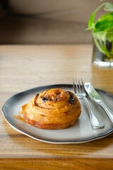 Croissant or Pain aux raisins or danish raisins roll on pottery plate. Roti