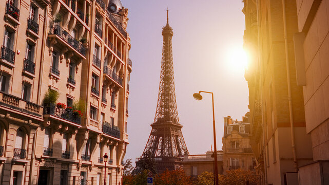 Sun shining over the Eiffel Tower framed by Parisian buildings at sunset