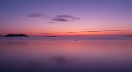 Obraz premium Serene Sunset over Misty Lake with Island Silhouette and Buoy