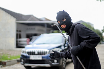 Suspicious Man Wearing a Hood Sneaking Near Vehicle in Parking Space to Break In. 